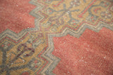 Distressed Oushak rug detail showing faded cinnabar red and serrated grey-gold contour.