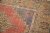 Stepped corner spandrel of distressed Oushak rug, concentric diamond, pinwheel, and faded cinnabar red.