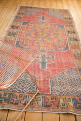 Faded cinnabar red field, distressed texture, starburst spandrel, and serpent border of the Oushak rug.