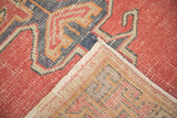 Close-up of distressed vintage Oushak rug showing faded cinnabar red pile and cotton selvage.