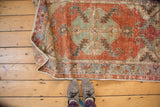 Folded vintage Distressed Oushak rug runner, showing serrated red medallion and faded blue patterns.