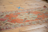 Faded madder red Oushak runner field with serrated blue-green medallion and corner motifs.