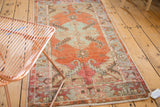 Distressed corner of a vintage Oushak rug with serrated cherry red border.