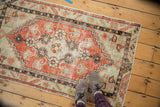 Distressed Oushak rug in faded brick red and ivory, showing diamond medallion and even wear.