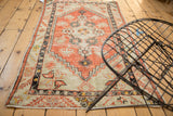 Distressed Oushak rug featuring diamond medallion, floral motif, and stepped border.