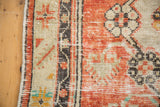 Distressed Oushak rug side: intact selvage, worn pile, brick red, ivory, charcoal border.
