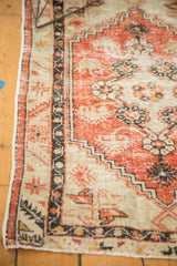 Distressed Oushak rug with faded brick red pile, charcoal meandering vine border, intact selvage.