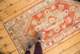 Distressed Oushak style runner showcasing worn cherry red pile and ivory floral motifs.