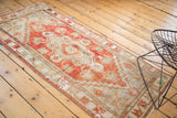 Vintage distressed Oushak runner showcasing worn cherry red and platinum floral motifs.
