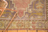 Vintage Oushak rug border showing germinating flowers in mauve and wine red, with aubergine field.