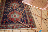 Antique Heriz rug with intricate serrated leaf border and indigo-red field pattern.