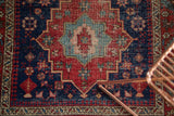 Antique Heriz rug corner: light blue starburst medallion, cherry red field, serrated main border.