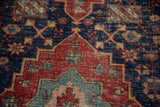 Antique Persian Heriz rug with cherry red medallion and intricate indigo field patterns.