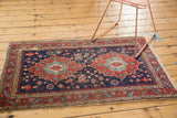 Antique Heriz rug corner: cherry red serrated leaf border and indigo field starbursts.