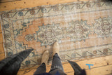 Distressed vintage Oushak runner with pale peach field and ivory geometric patterns showing visible wear.