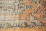 Distressed Oushak runner border featuring pale peach, antique ivory, and dusty teal florals.