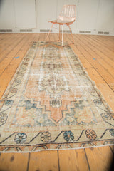 Distressed peach, ivory, and dusty teal floral border of a vintage Oushak runner.