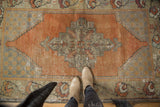 Distressed geometric stepped medallion on vintage Oushak rug with faded orange.