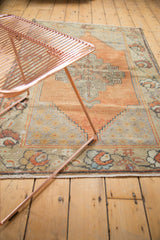 Vintage distressed Oushak rug featuring faded orange palmettes and geometric patterns.
