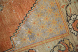 Distressed Oushak rug detail: faded burnt orange field, slate blue starburst lattice.