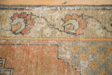 Distressed Oushak rug detail with faded orange palmettes, geometric elements, and visible worn pile.