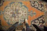 Vintage Oushak rug's octagonal medallion and rococo spandrels in faded orange and blue.
