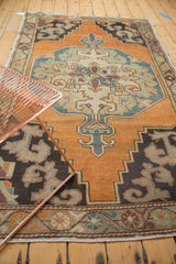 Vintage Oushak rug with low pile, faded burnt orange field, and rococo serpent motifs.