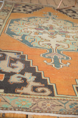 Vintage Oushak rug corner with burnt orange field, low pile, and charcoal rococo motifs.