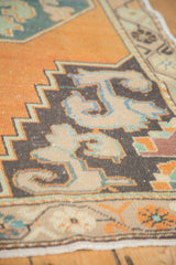 Burnt orange Oushak rug corner with charcoal, beige, powder blue stepped patterns, low pile.