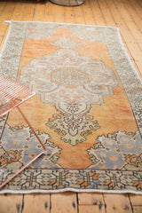 Faded tangerine orange and slate blue grey Rococo patterns on a distressed vintage Oushak rug.