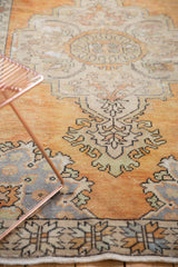 Distressed Oushak corner with faded tangerine, ivory, slate blue Rococo-style patterns.