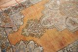 Scalloped Rococo motifs in distressed tangerine orange and slate blue grey Oushak rug.