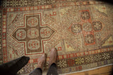 Distressed Anatolian runner with faded brick red rectilinear medallions and hook motifs.