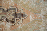 Close-up of distressed Turkish Oushak rug texture, showing low pile and foundation in geometric sage, mauve, charcoal.