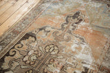 Distressed vintage Oushak rug close-up: visible foundation wear, abrash, and muted brown and sage design.