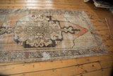 Distressed Oushak rug corner, revealing pale mauve, slate blue tones, and visible foundation.