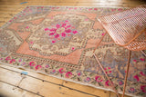 Distressed Oushak rug with bright pink floral medallion and soft blue rococo spandrels.