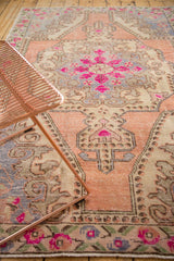 Vintage distressed Oushak rug rococo corner spandrel with bright pink motifs and soft wear.