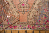 Distressed Oushak rug border with bright pink floral motifs, blush field, and rococo corner.
