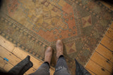 Faded aubergine and bronze distressed vintage Oushak rug with pinwheel corner spandrel.