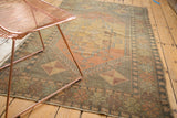 Distressed corner of a vintage Oushak rug, showing faded bronze and burnt orange pinwheel design.