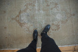 Distressed vintage Oushak rug showing worn pile texture and faded ivory-bronze pattern.