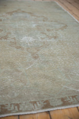 Distressed vintage Oushak rug with worn ivory pile and faded bronze geometric border.