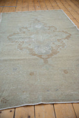 Close-up of distressed Oushak rug texture, showing mostly even wear and faded bronze pattern.