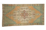 Distressed vintage Oushak runner with an apricot medallion, faded teal spandrels, and geometric patterns.