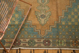 Distressed Oushak rug corner showing faded apricot, teal stepped spandrel and floral border.