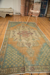 Oushak rug corner with distressed apricot field, faded teal spandrel, and visible even wear.