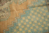 Distressed texture of stepped apricot border with faded teal and sand geometric motifs.