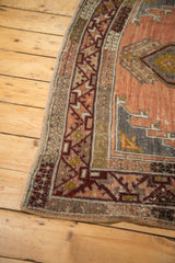Distressed Anatolian rug runner's corner with worn pile, geometric terracotta and charcoal patterns.