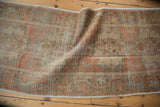 Vintage distressed Oushak runner showing faded burnt orange, brown rococo motifs, and visible foundation.